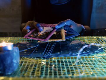 A woman’s hands fanning out three cards for an oracle card session