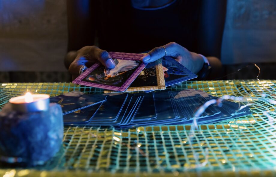 A woman’s hands fanning out three cards for an oracle card session