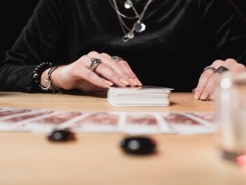 selective focus of female psychic laying tarot cards near divination stones